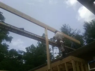Carpenter setting a ridge beam over a new addition frame — Ice Dam Removal by Roofing Brothers in Slater