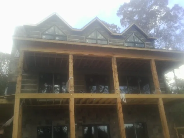 Dormers and porch framing on a large log home under construction — Roof Coating work by our crew in Slater