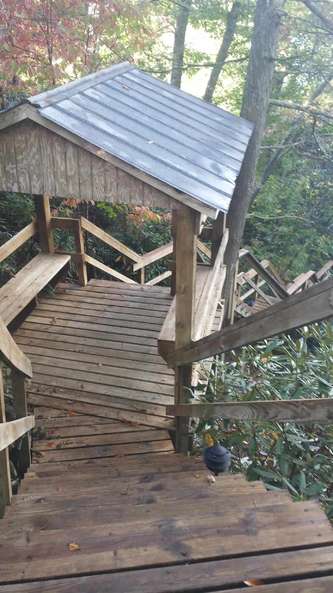 Metal roofed shelter over wooden steps on a wooded walkway — Skylight Repair & Installation work by our crew in Slater